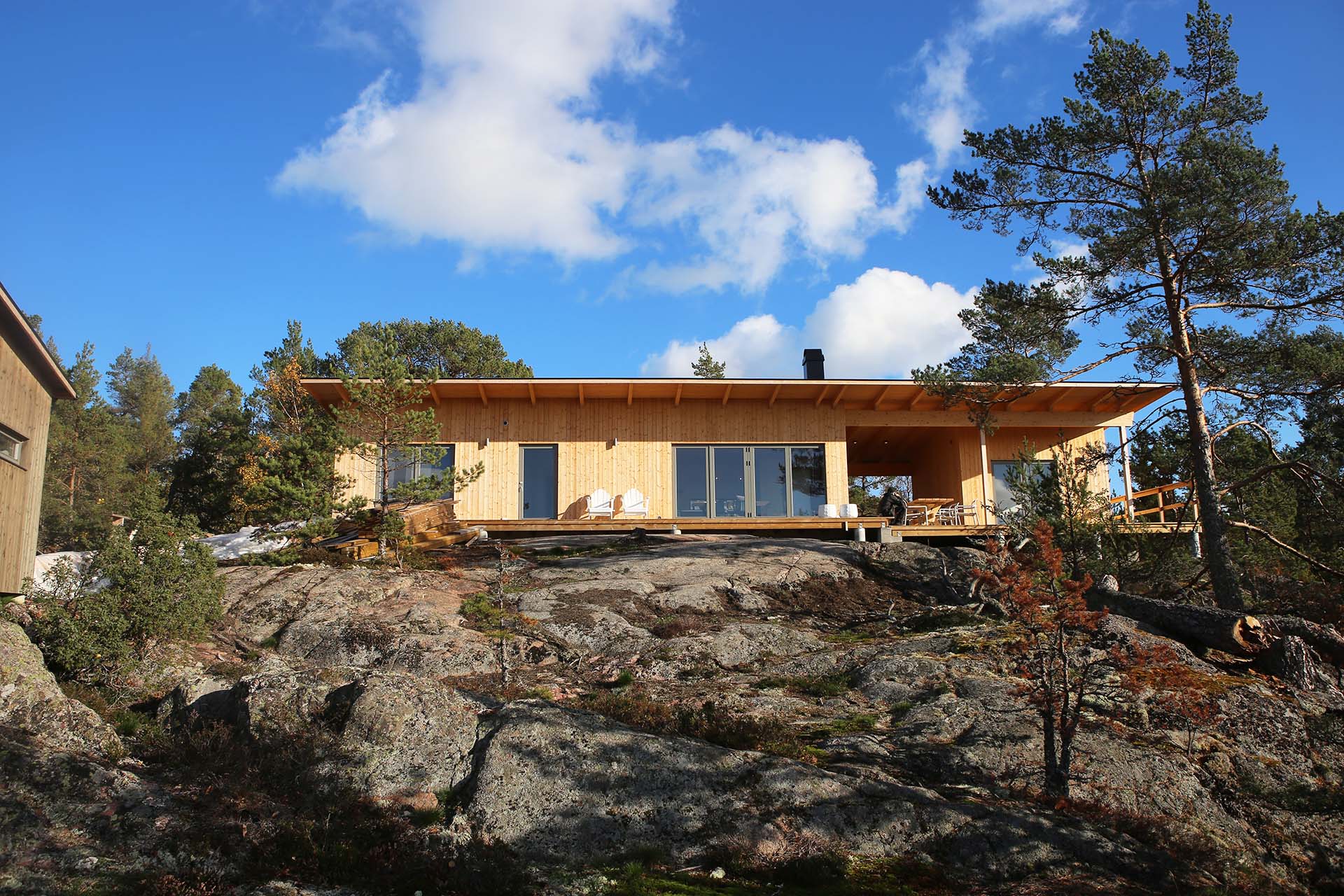 Ett fritidshus i trä med utstickande tak ligger högst upp på en klippa i Stockholms skärgård. Arkitekt är Anders Frelin.