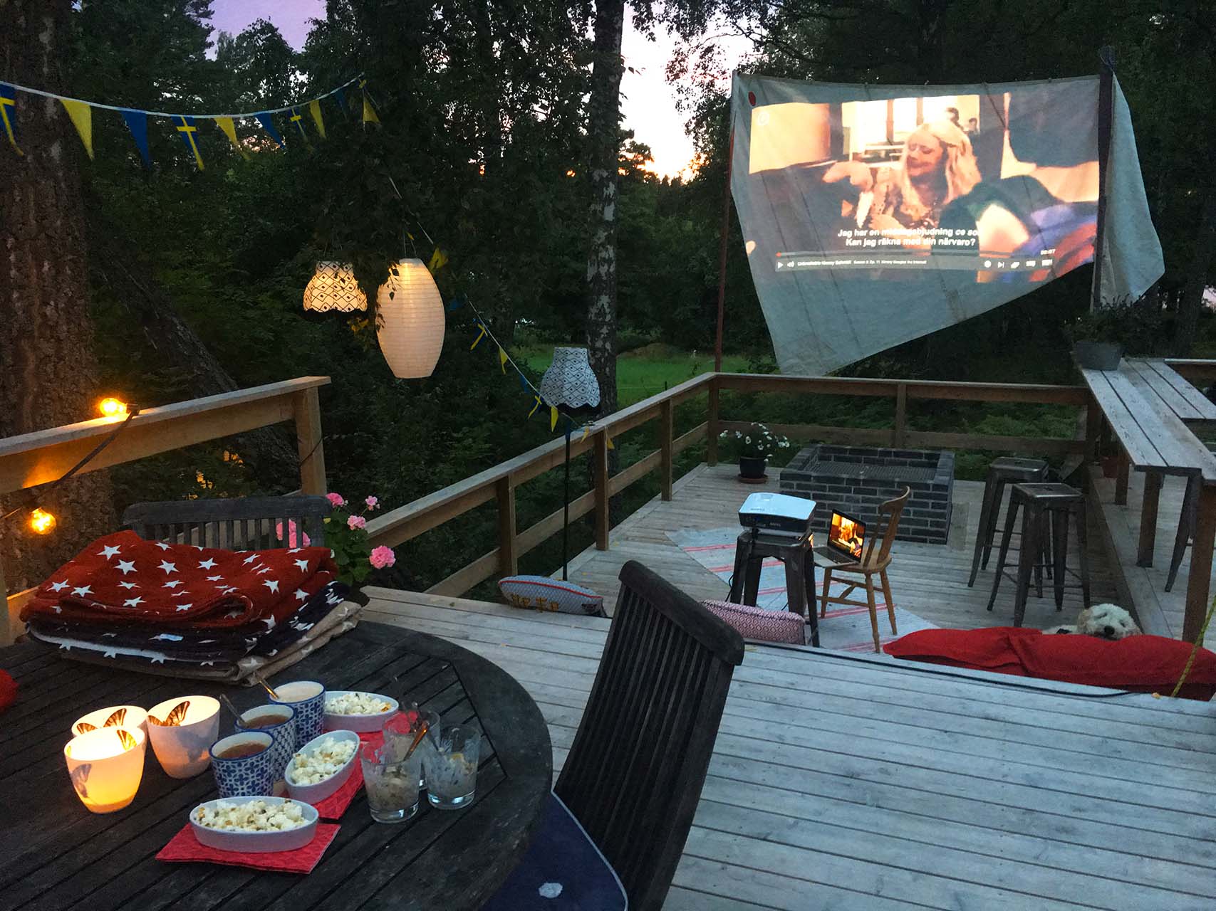 Utomhusbio en kväll på en veranda med utekök, bar och murad eldstad. Filmen visas på en segelduk. Arkitekt är Anders Frelin.