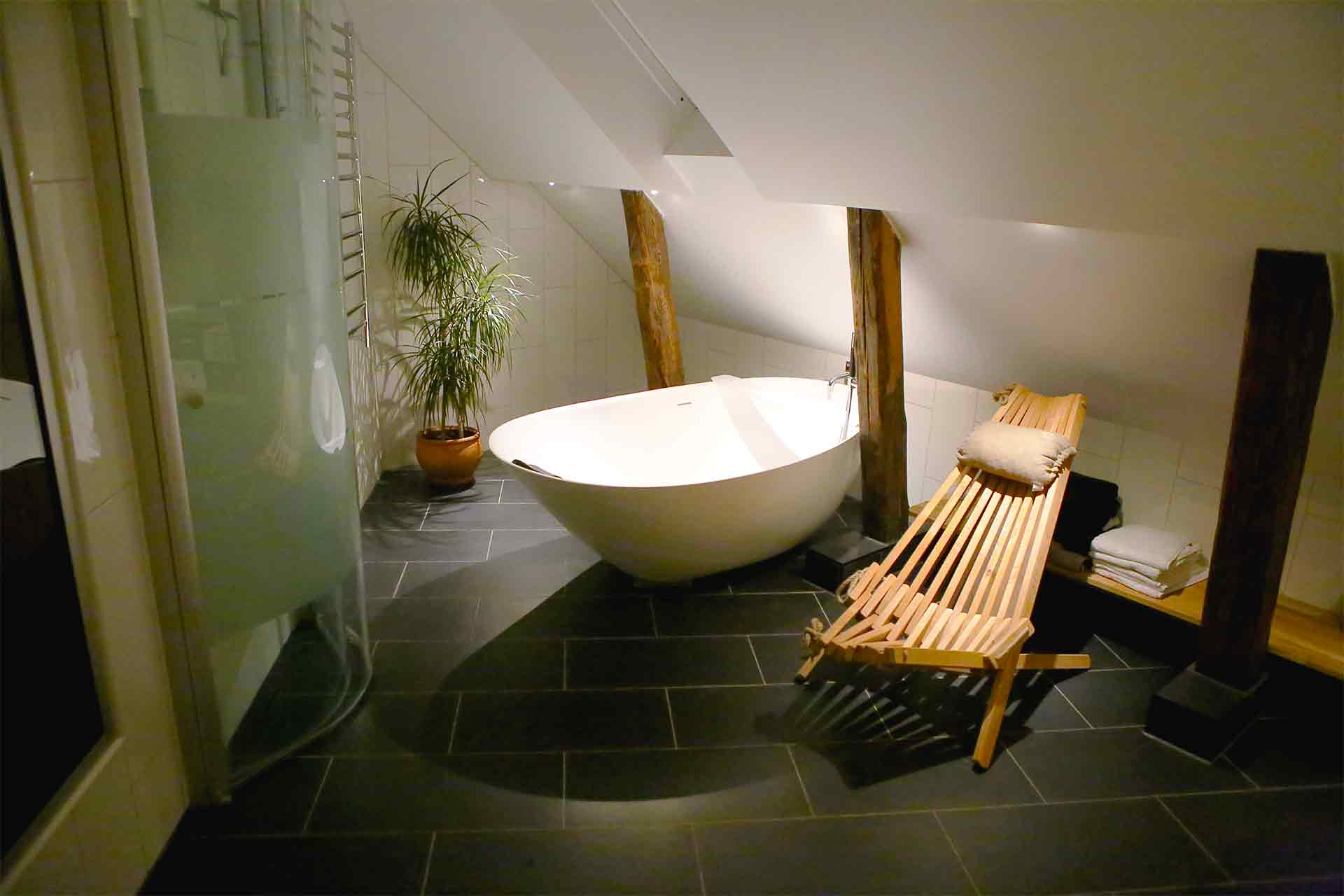 Ett stort ovalt badkar och en vilstol lyses upp i ett vindsbadrum ritat av arkitekt Anders Frelin.
