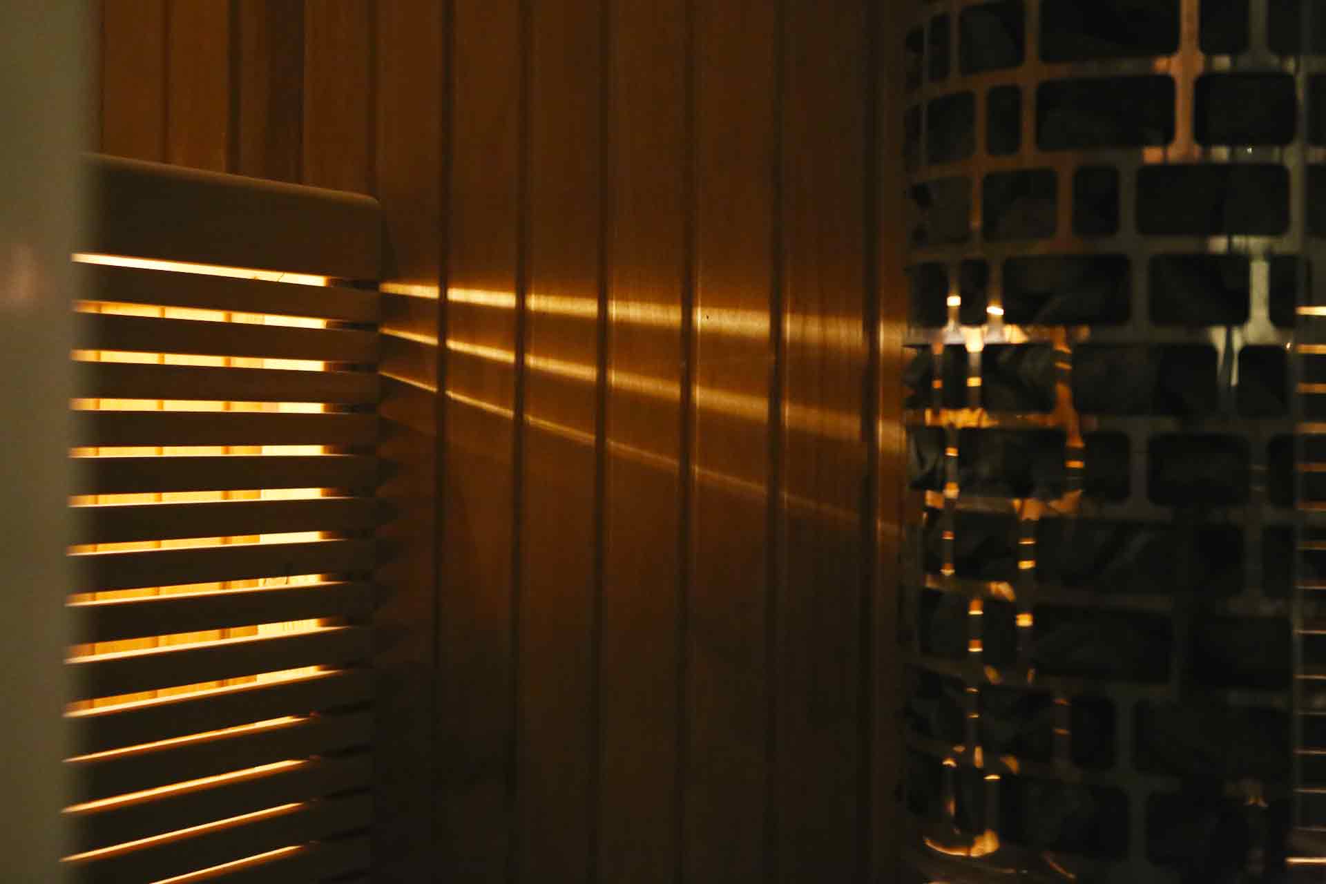 Ett bastuaggregat lyses upp av ljus under en bastulav i ett vindsbadrum ritat av arkitekt Anders Frelin.
