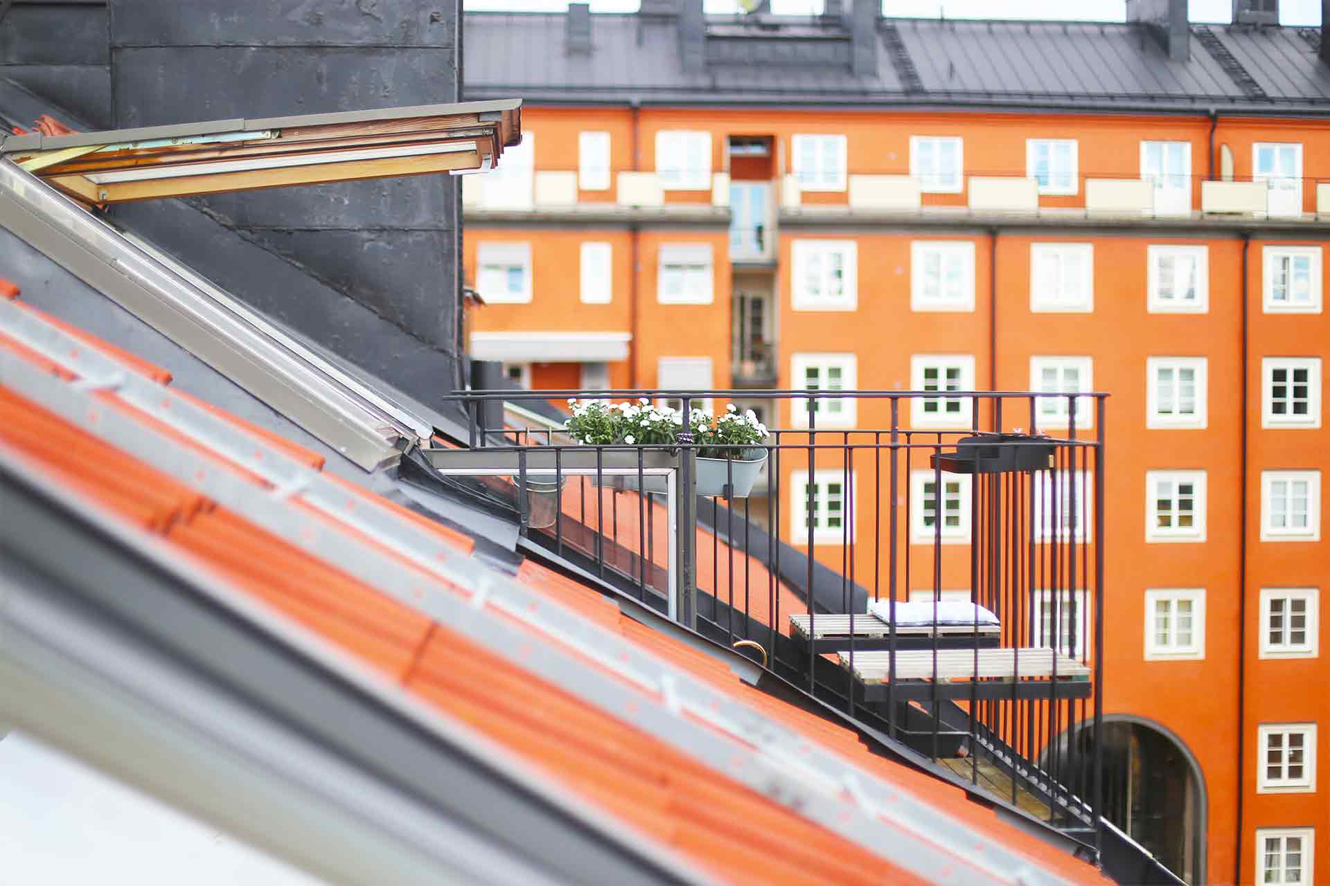Vindslägenhetens takbalkong med tunt smidesräcke smyger fram bland färgglada sekelskifteshus. Arkitekt är Anders Frelin.